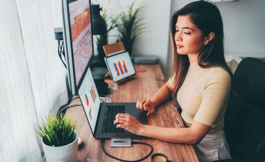 A remote office worker looking at the financial graph on her computer screen