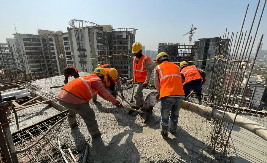 A team of construction workers mixing cement on top of the building they are building