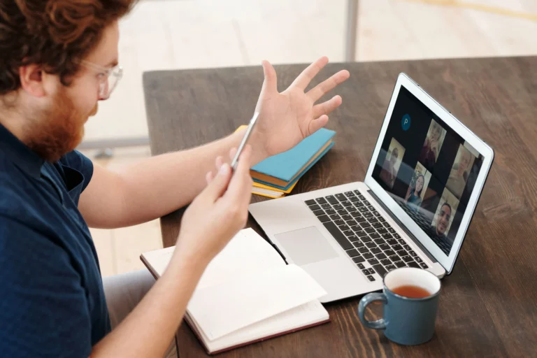A business owner sitting at his desk, leading a virtual video meeting with his remote team acquired via BPO services.